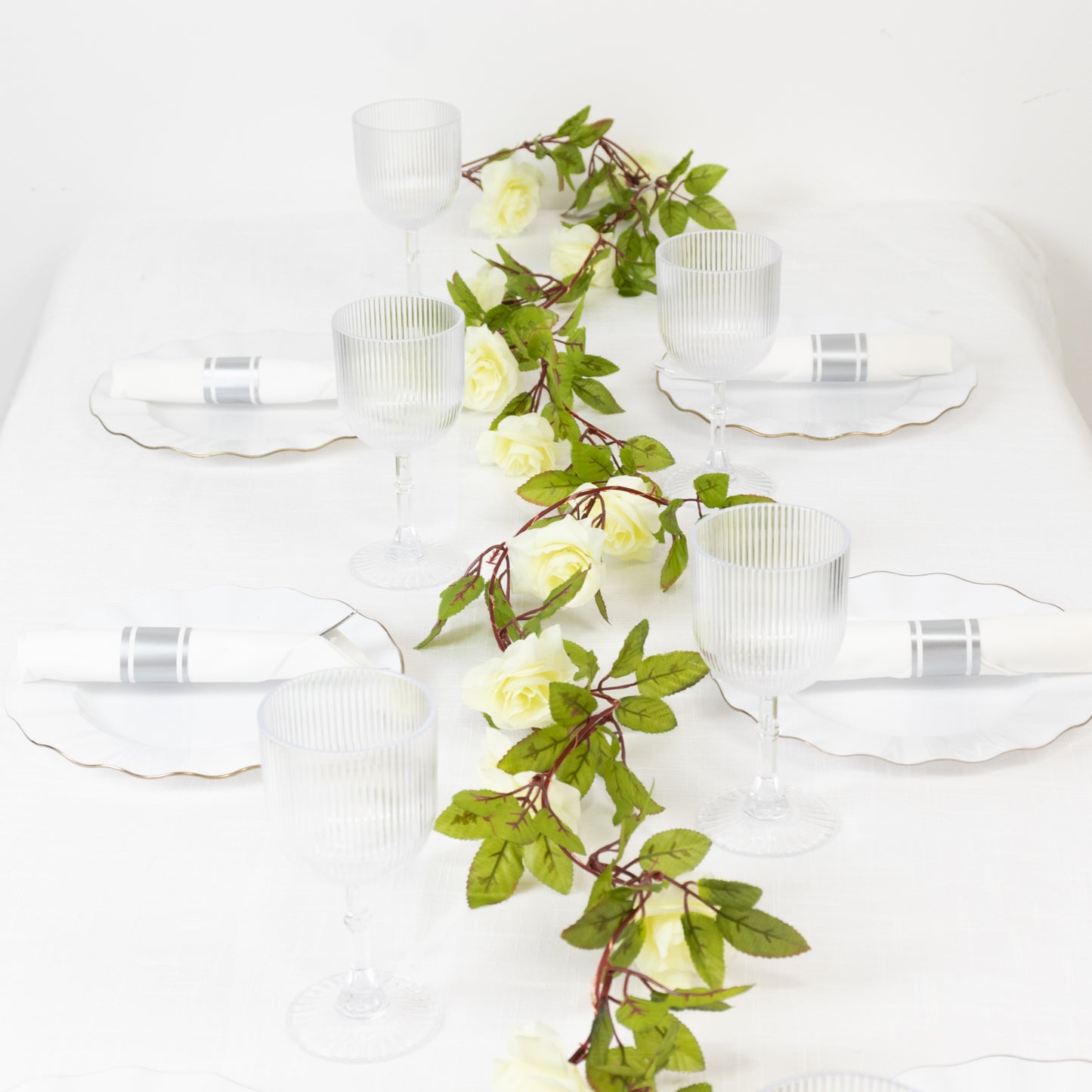 Warm white silk rose flower garland vine string lights on a table setting.