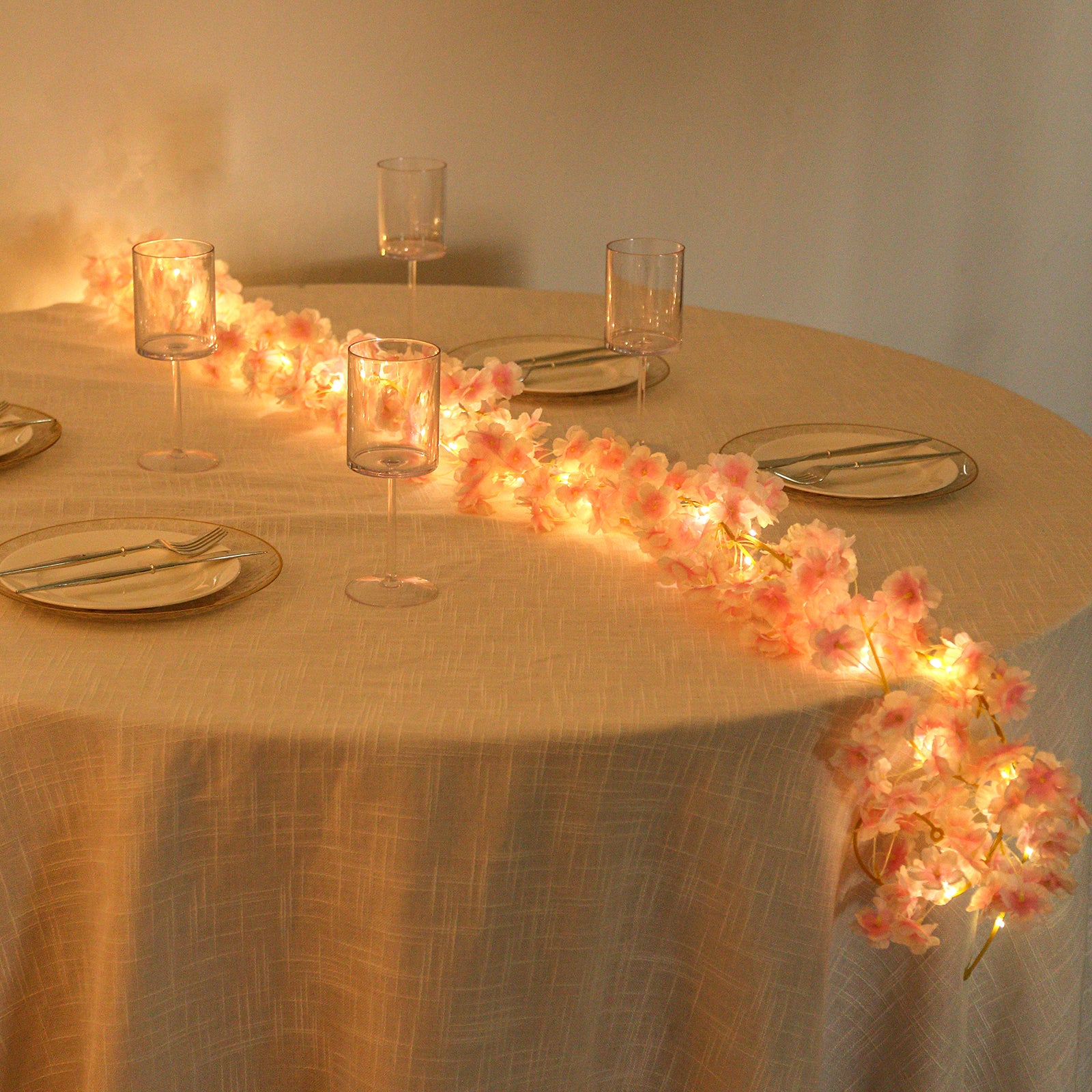 Blush cherry blossom garland LED string lights on a table setting.