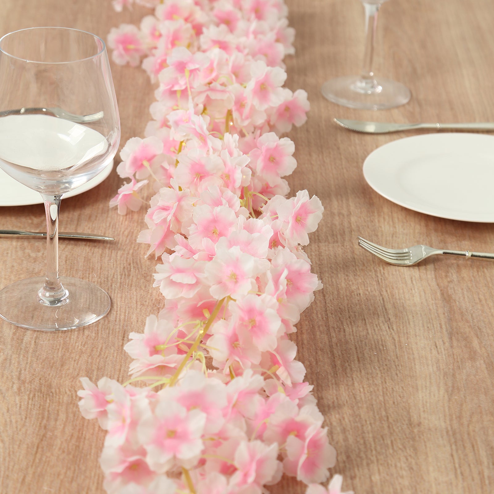 Blush cherry blossom garland LED string lights on a wooden table.