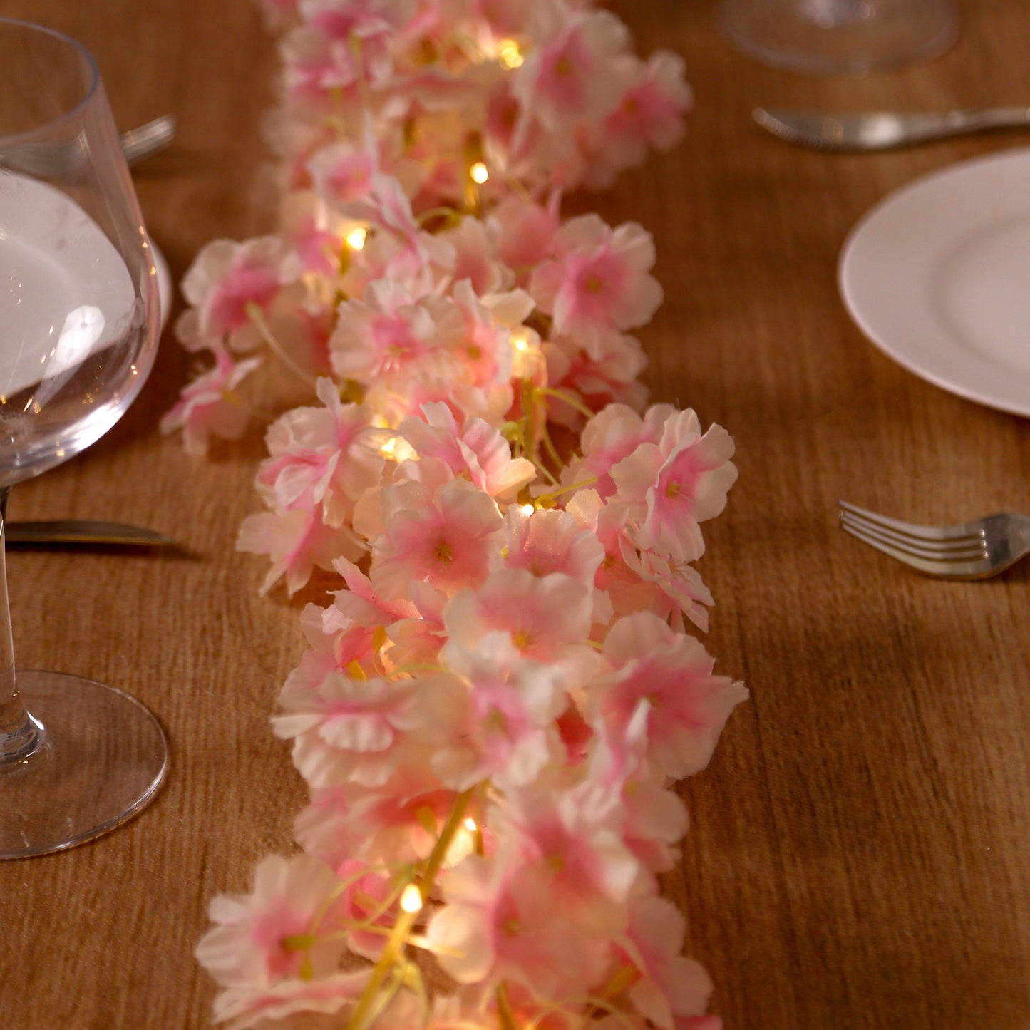 Blush artificial cherry blossom garland string lights with warm white LEDs.