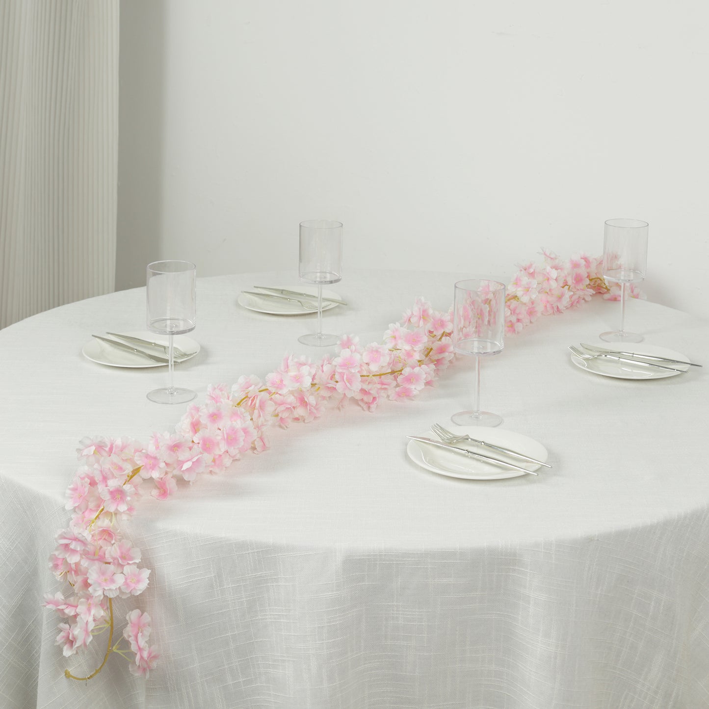 Blush artificial cherry blossom garland LED string lights on a table setting.