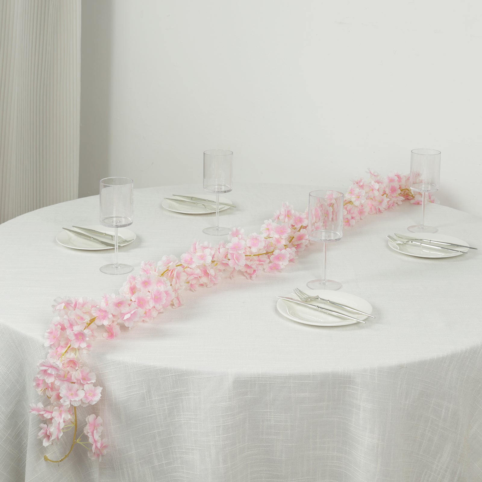 Blush artificial cherry blossom garland LED string lights on a table setting.