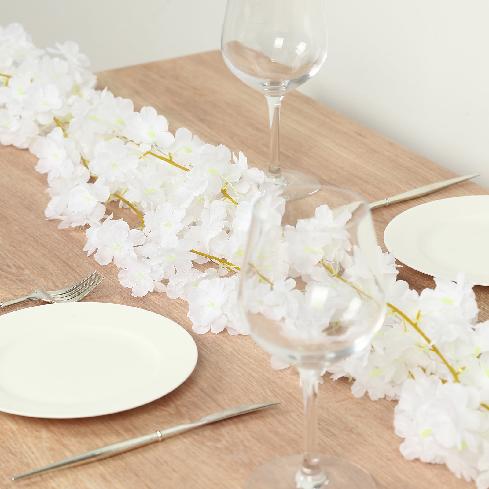 White artificial cherry blossom garland LED string lights on a wooden table.