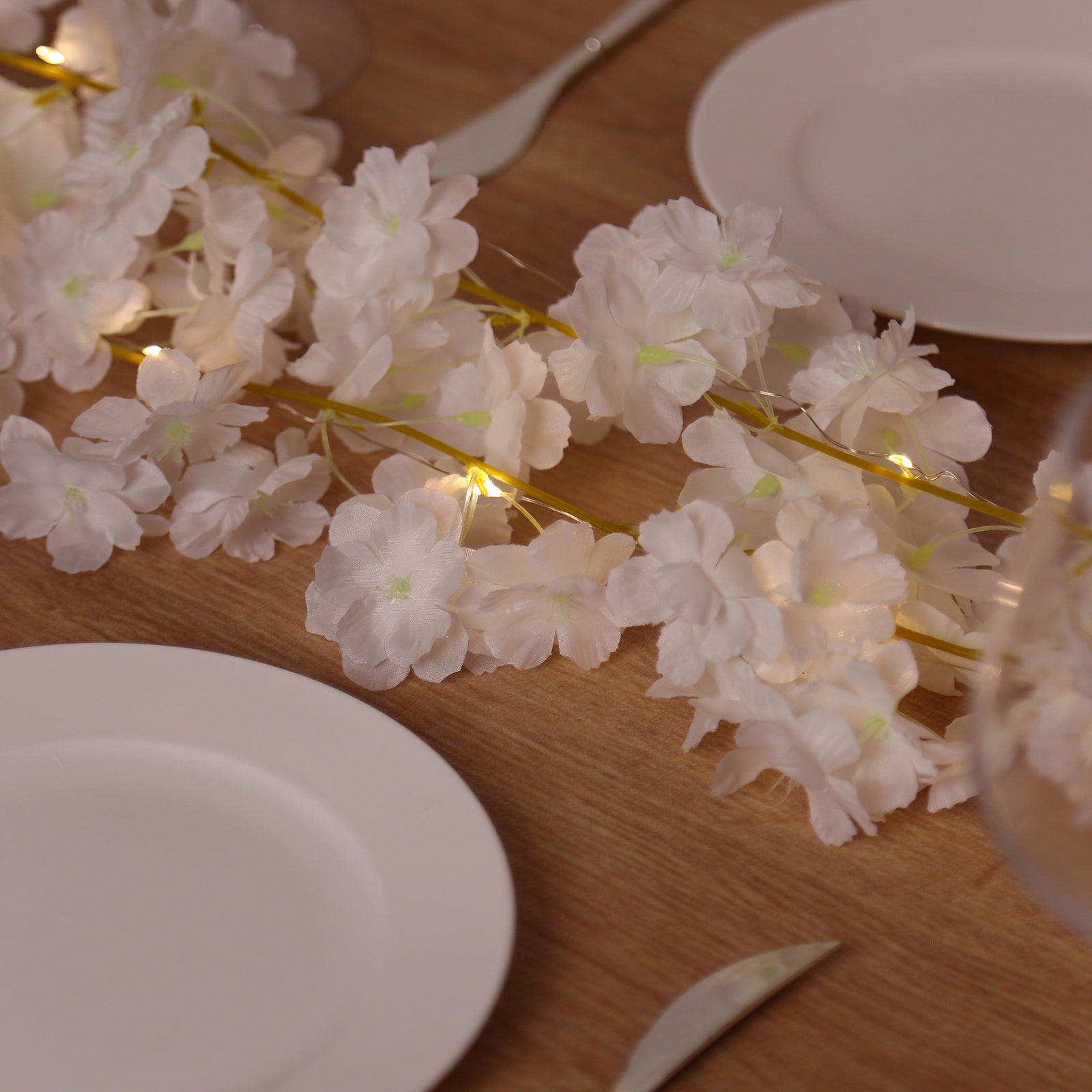 Warm white cherry blossom garland LED string lights on a wooden table.