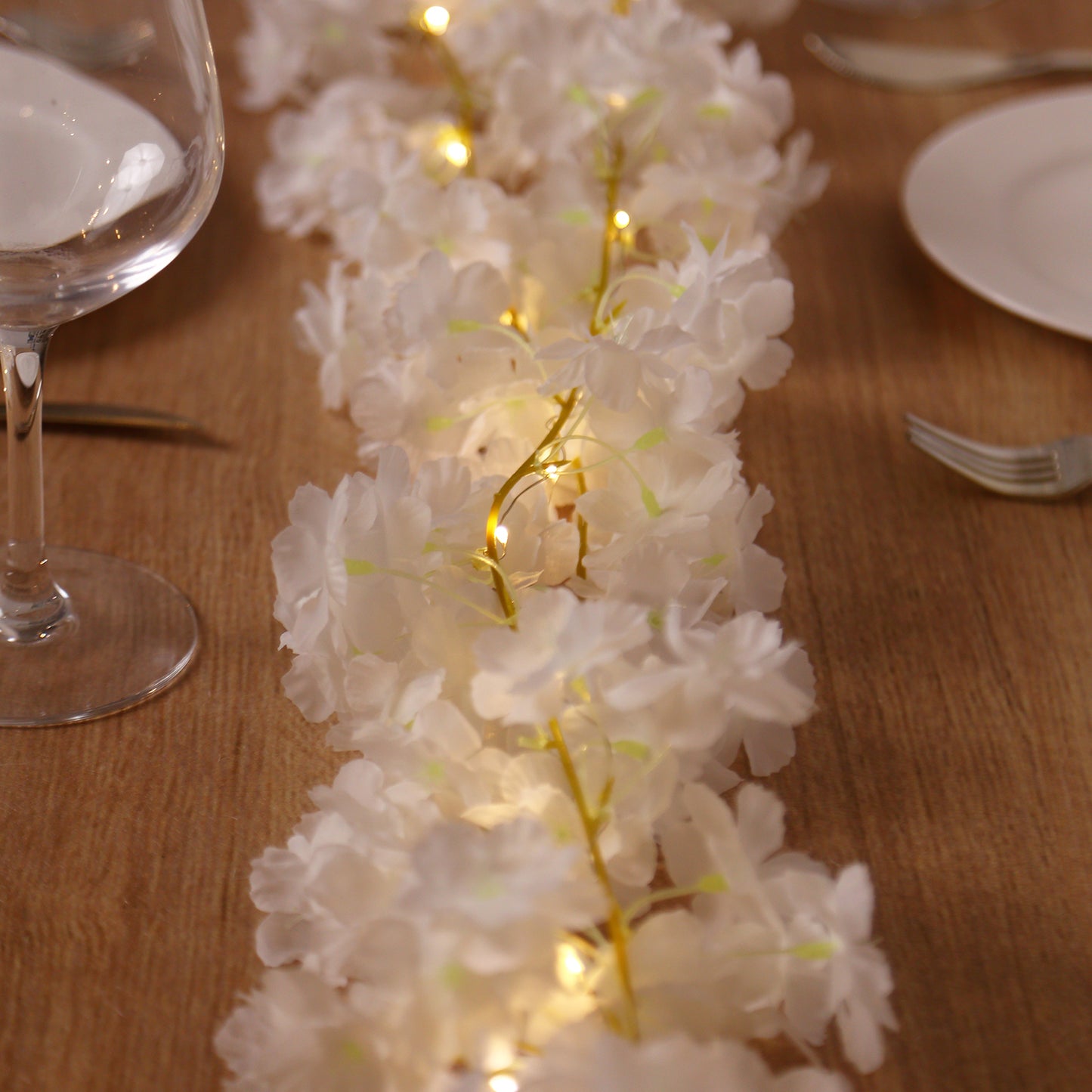 Warm white cherry blossom garland LED string lights on a table setting.