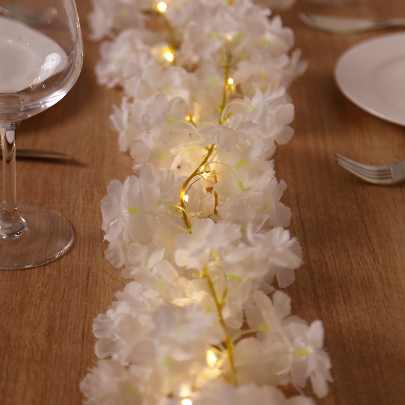 Warm white cherry blossom garland LED string lights on a table setting.
