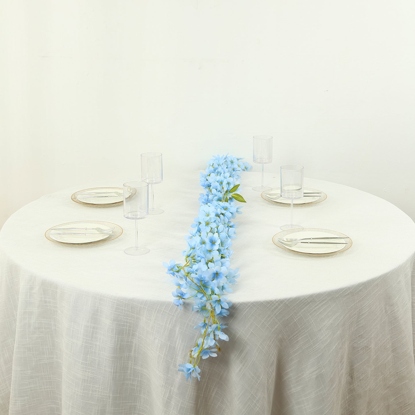 Blue jasmine silk flower garland with warm white LED lights on a table.