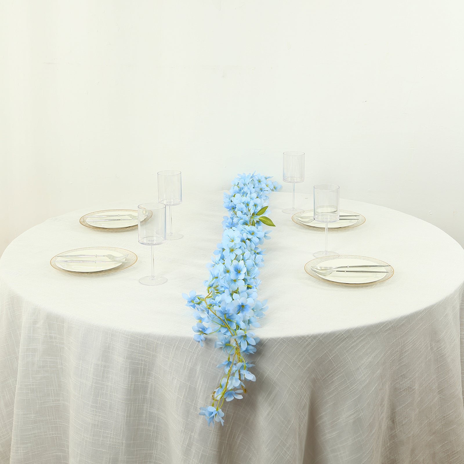 Blue jasmine silk flower garland with warm white LED lights on a table.