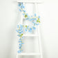 Blue jasmine silk flower garland with warm white LED lights on a white ladder.
