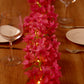 Pink jasmine silk flower garland fairy lights on a table.