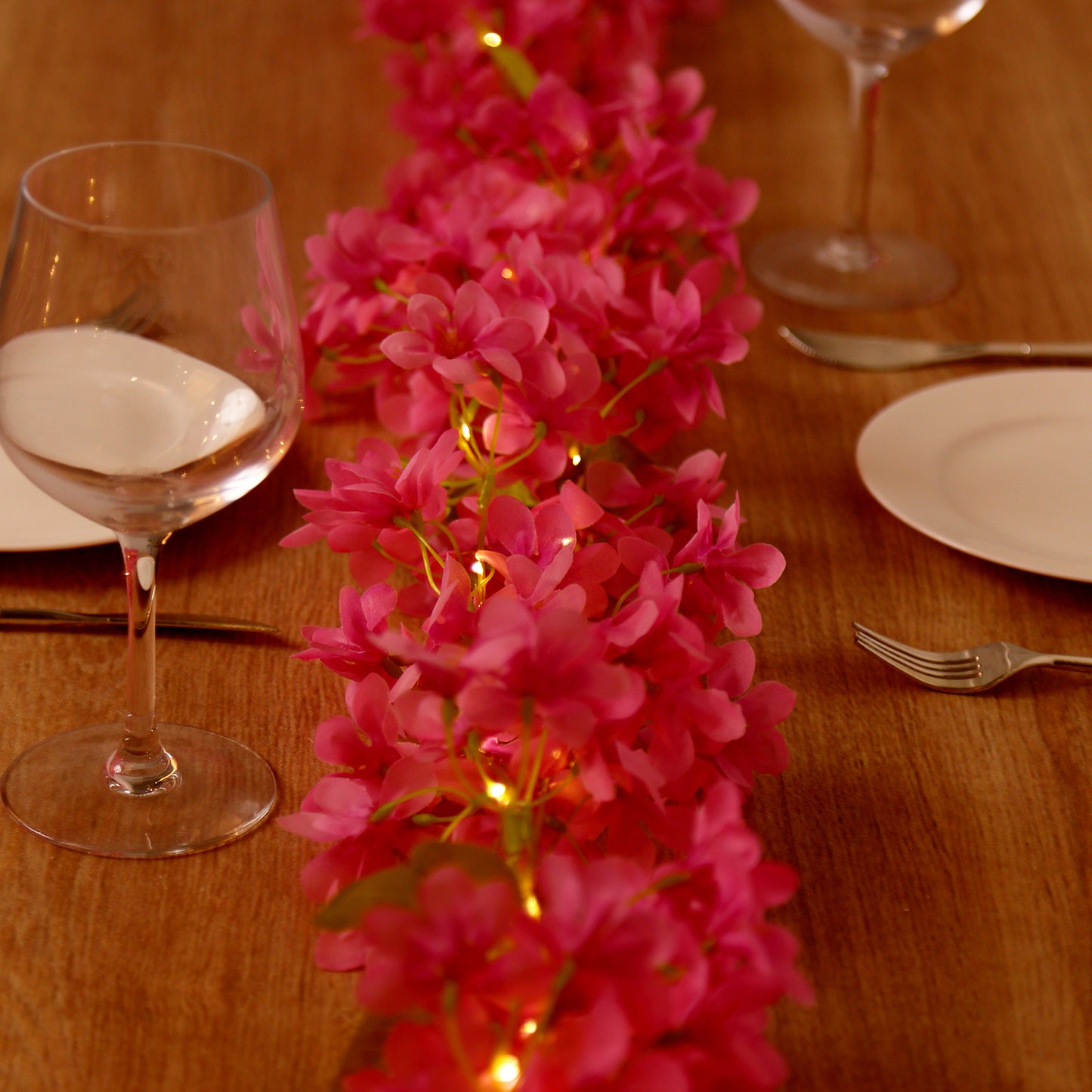 Pink jasmine silk flower garland fairy lights on a table.