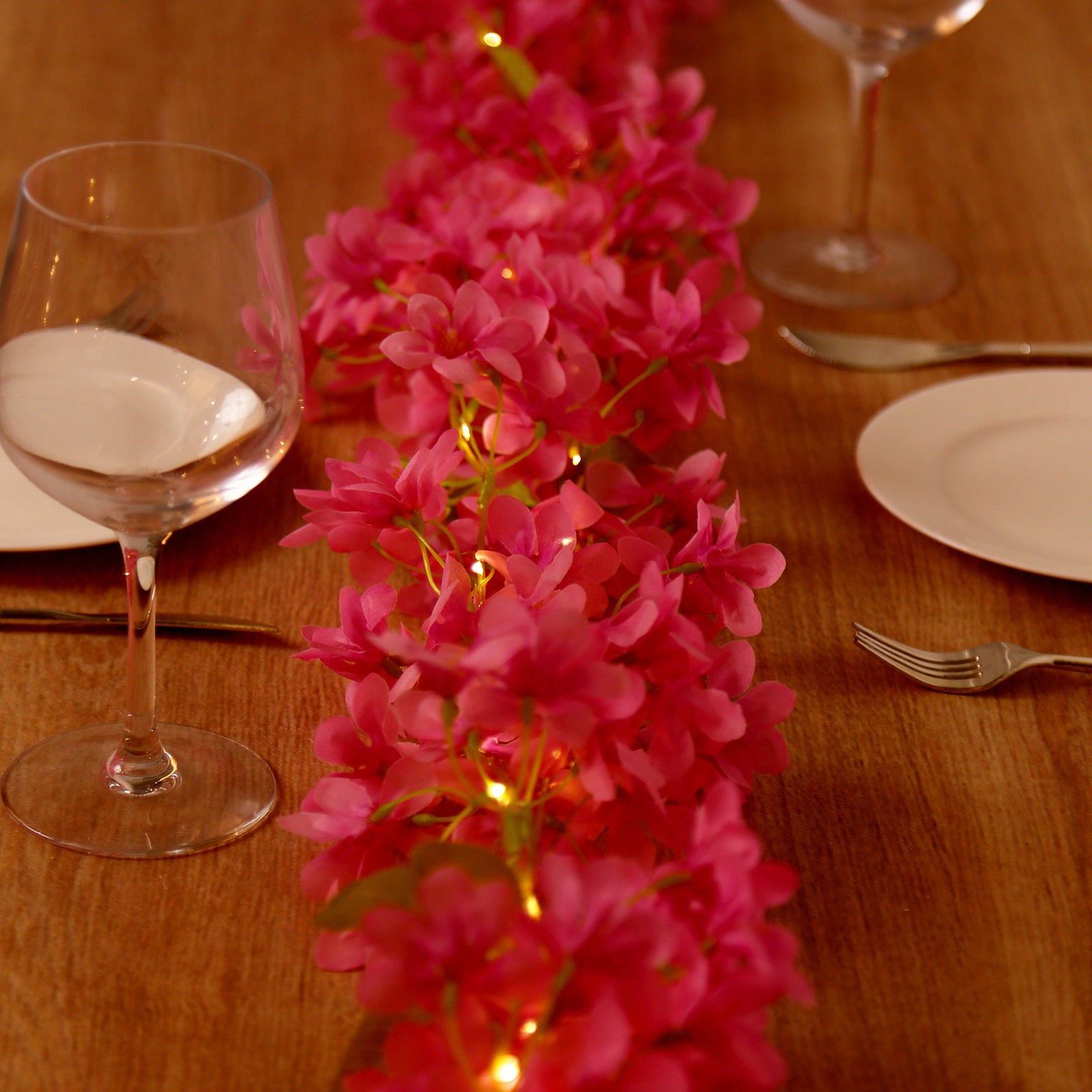 Pink jasmine silk flower garland fairy lights on a table.
