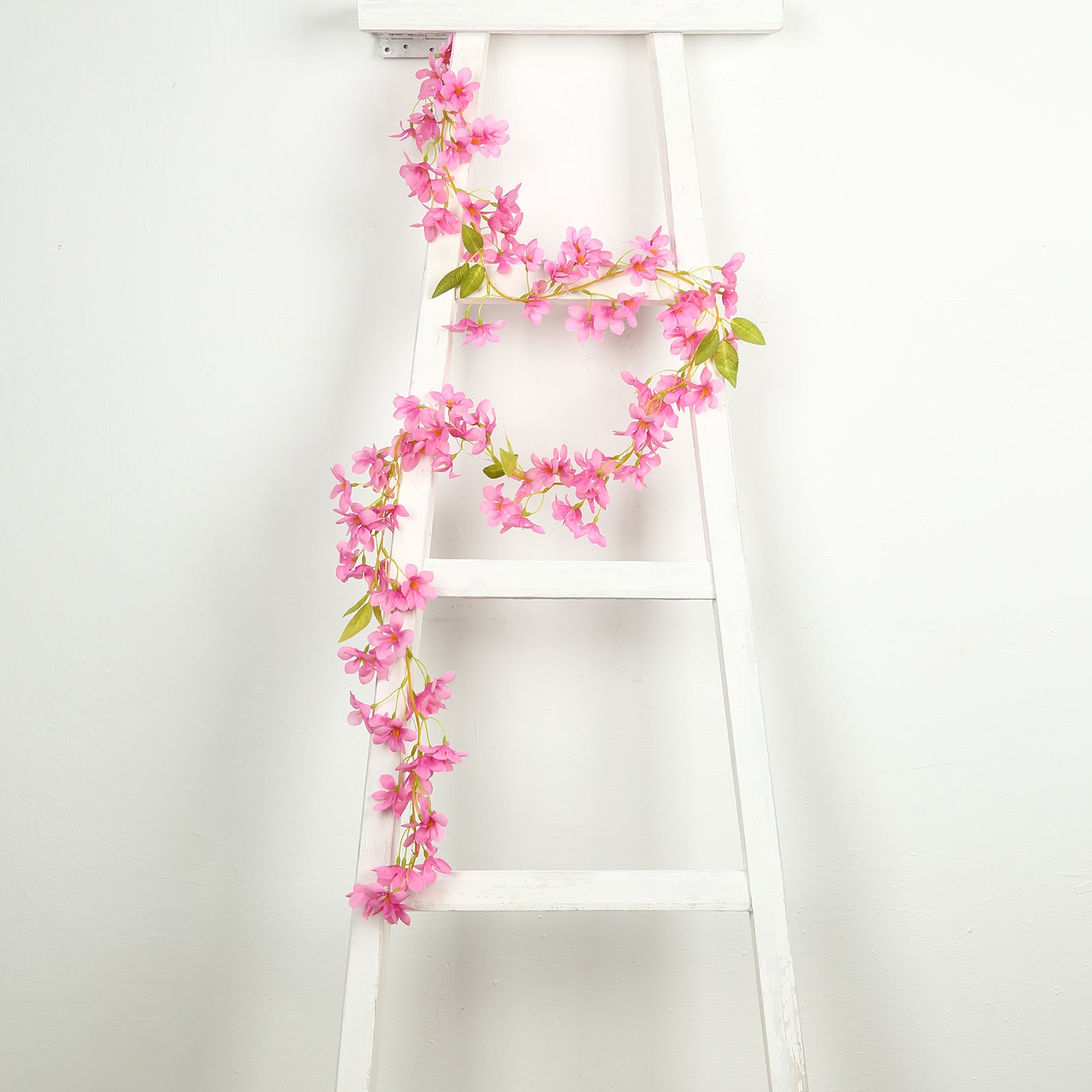 Pink jasmine flower garland with warm white LED lights on a white ladder.