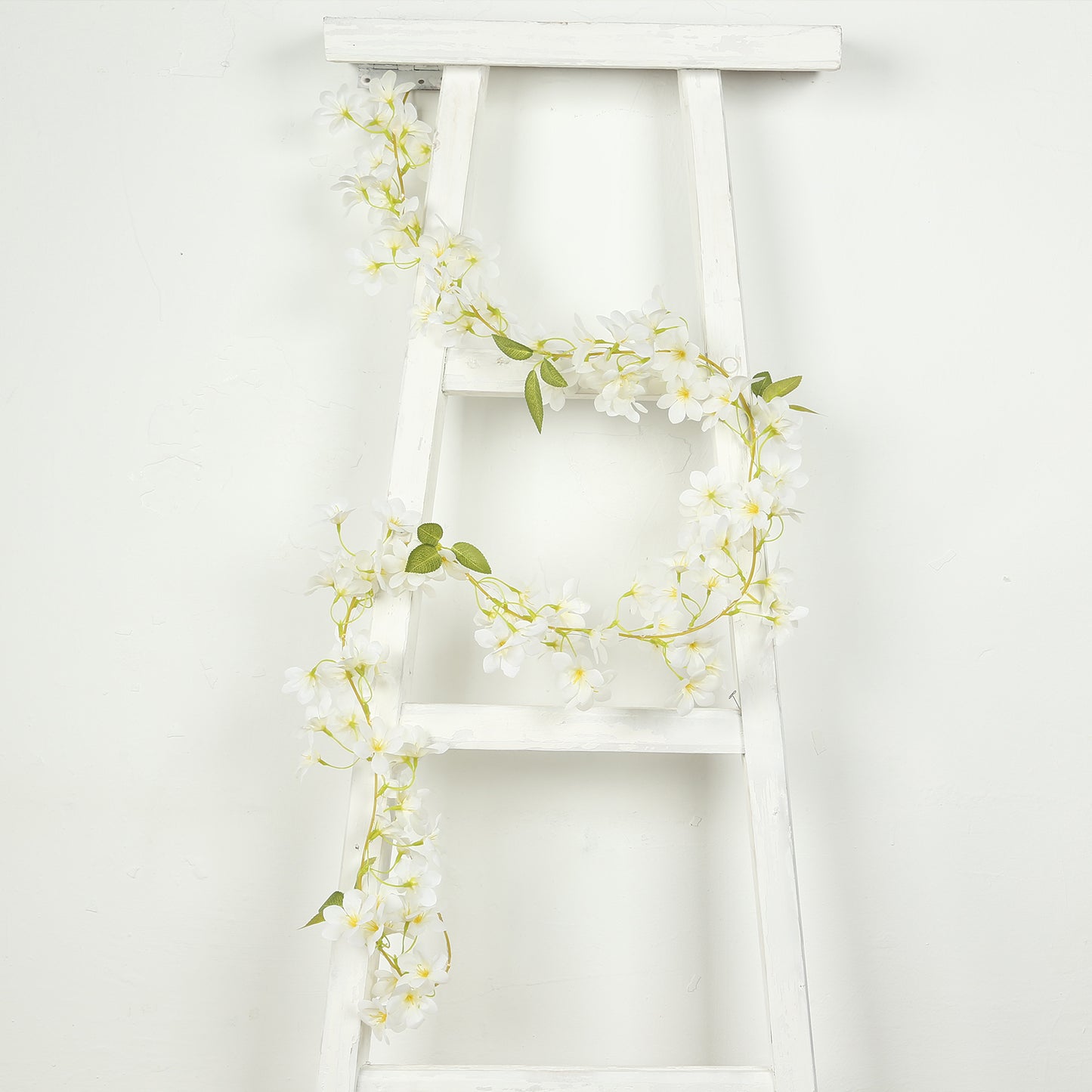 White jasmine flower garland with warm white LED lights on a ladder.