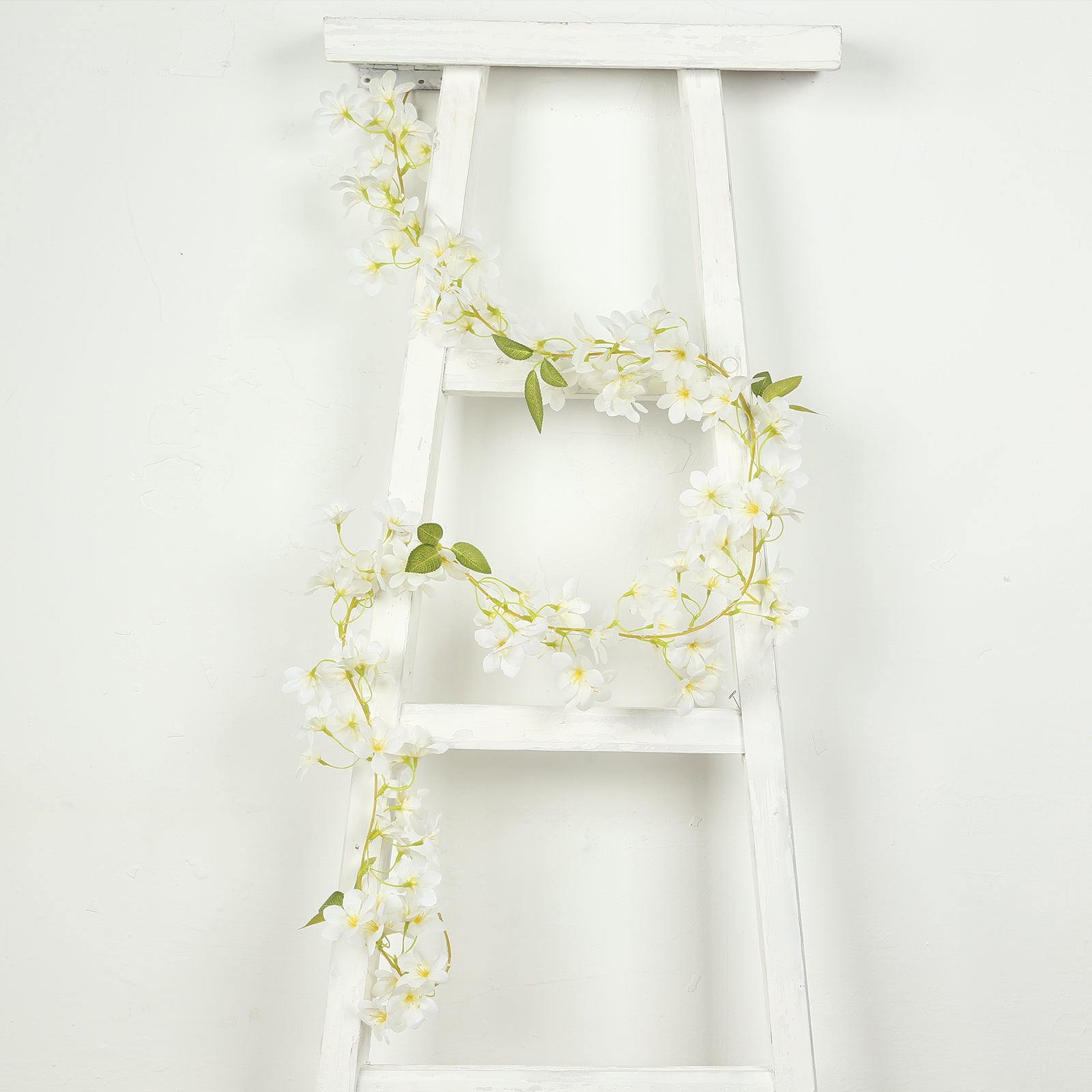 White jasmine flower garland with warm white LED lights on a ladder.