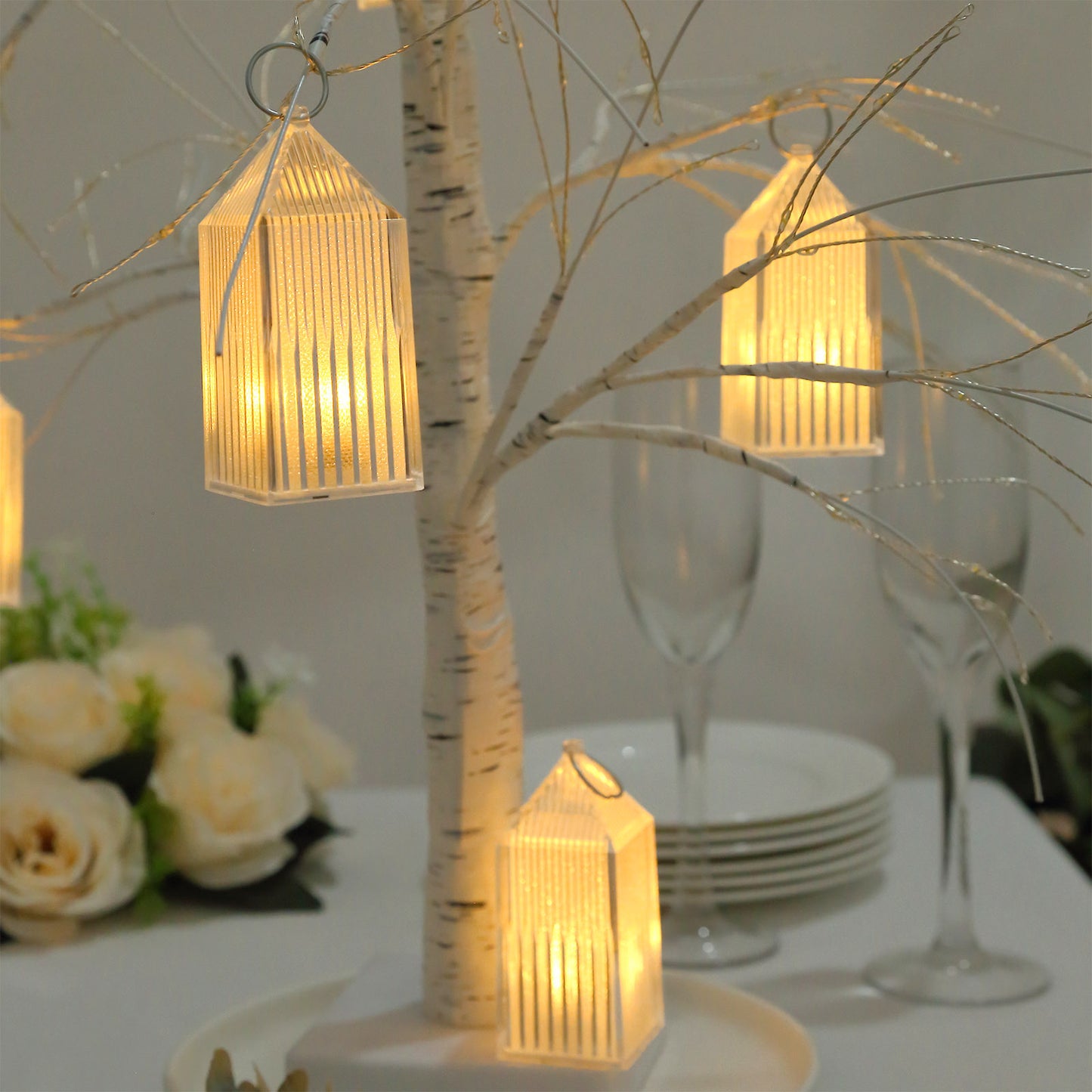 Clear warm white mini lanterns hanging from a decorative tree centerpiece.