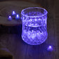 Light blue mini LED balls in a crystal glass with a wooden background.