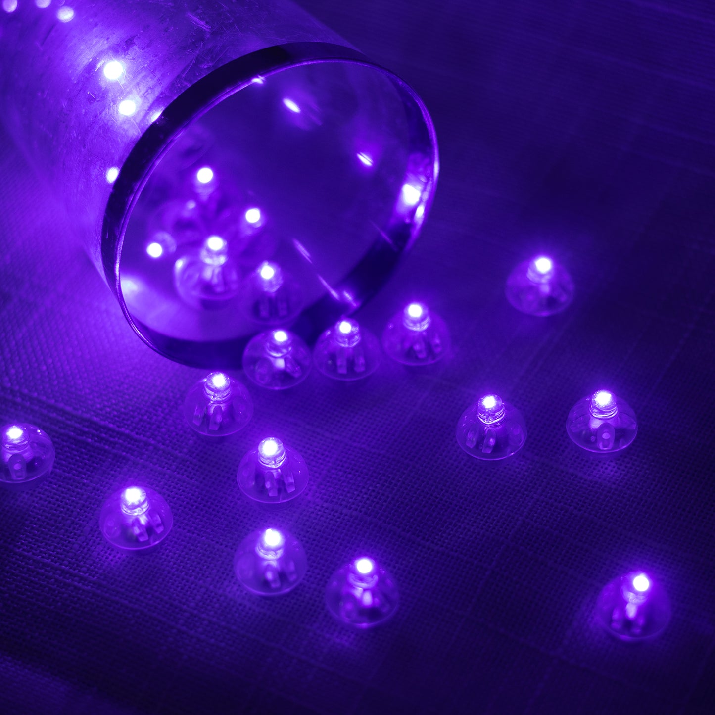 Purple mini LED balls scattered on a surface with a glass.