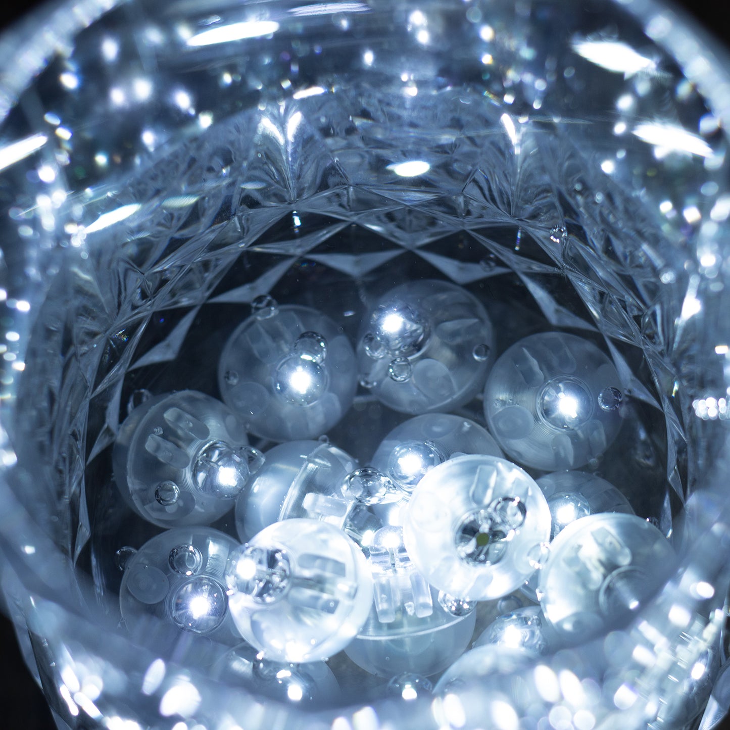 White round mini LED balls in a crystal bowl, glowing softly.