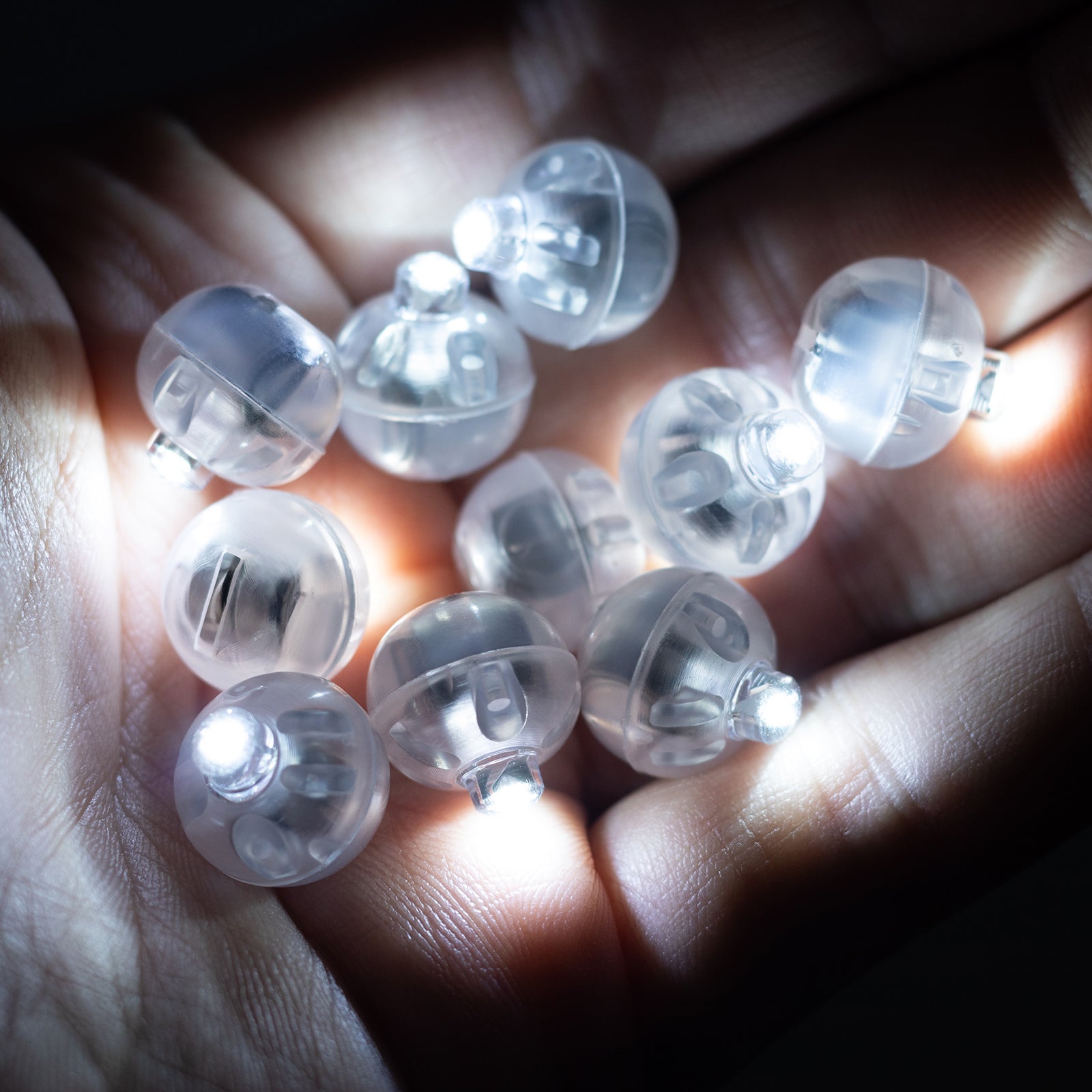 White mini LED balls in hand, battery-operated and waterproof.