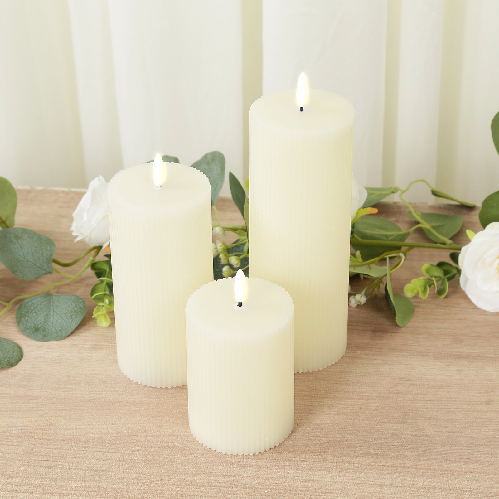 Ivory LED flameless pillar candles with ribbed design on a wooden surface.