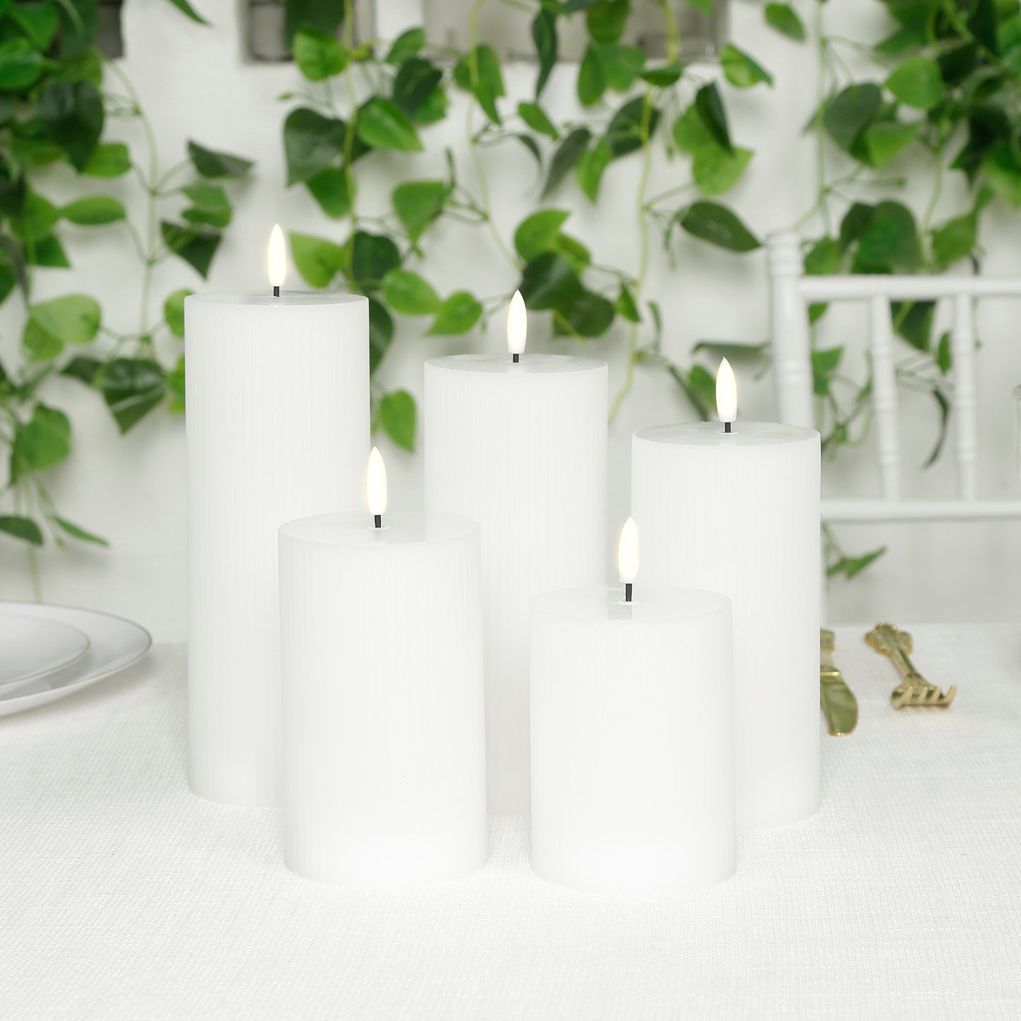 White LED flameless pillar candles in a ribbed design, flickering on a table.