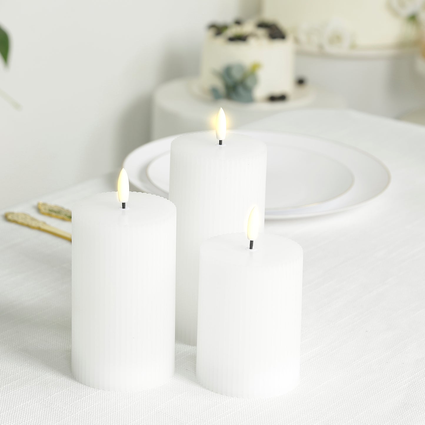 White LED flameless pillar candles with ribbed design on a table.