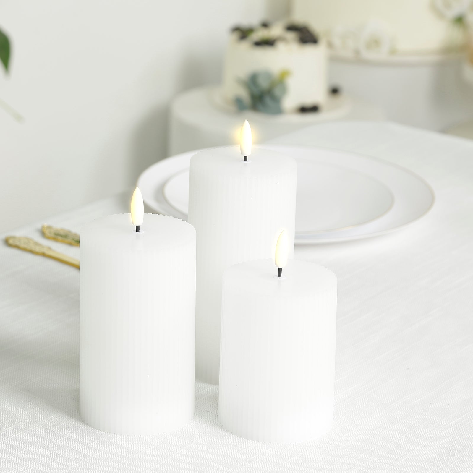 White LED flameless pillar candles with ribbed design on a table.