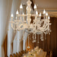 Silver crystal chandelier with LED candle bulbs above an elegant dining table.