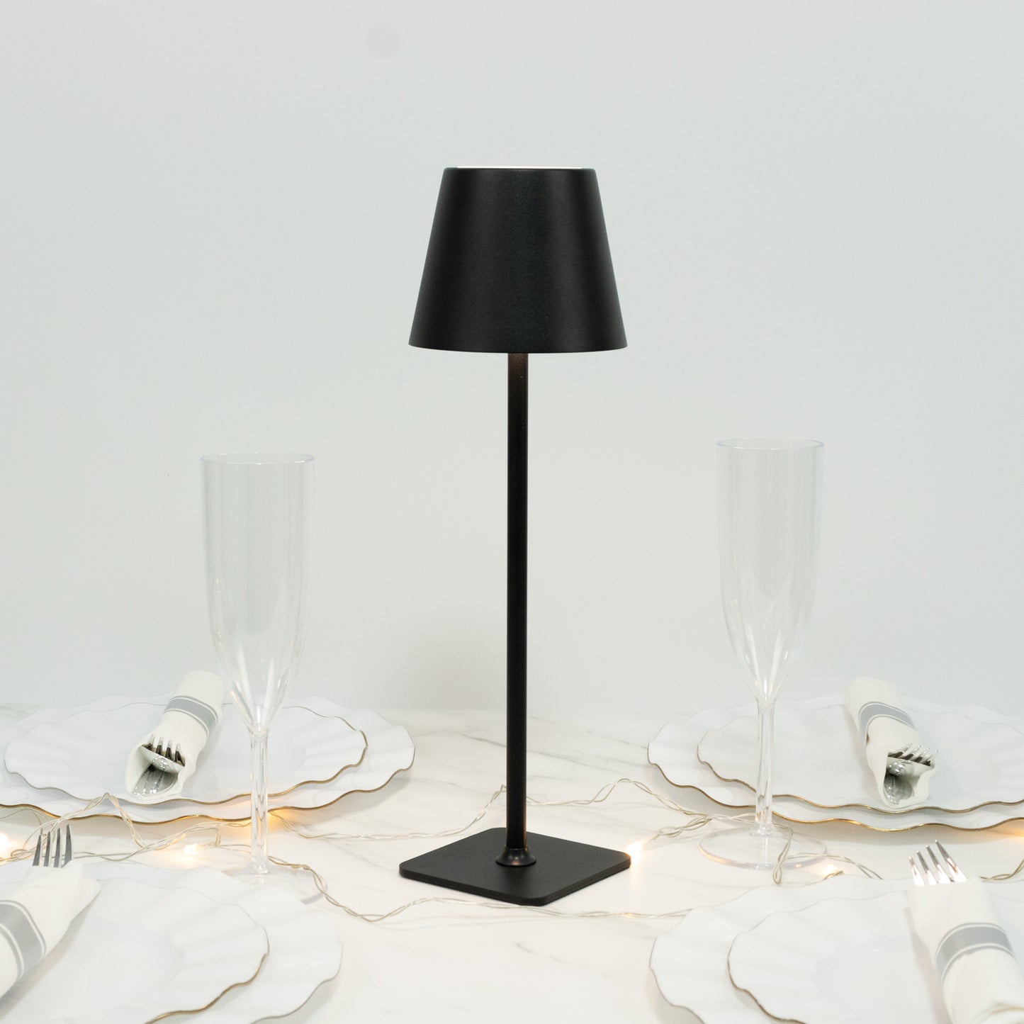 Black metal LED table lamp with classic empire lampshade on a dining table.