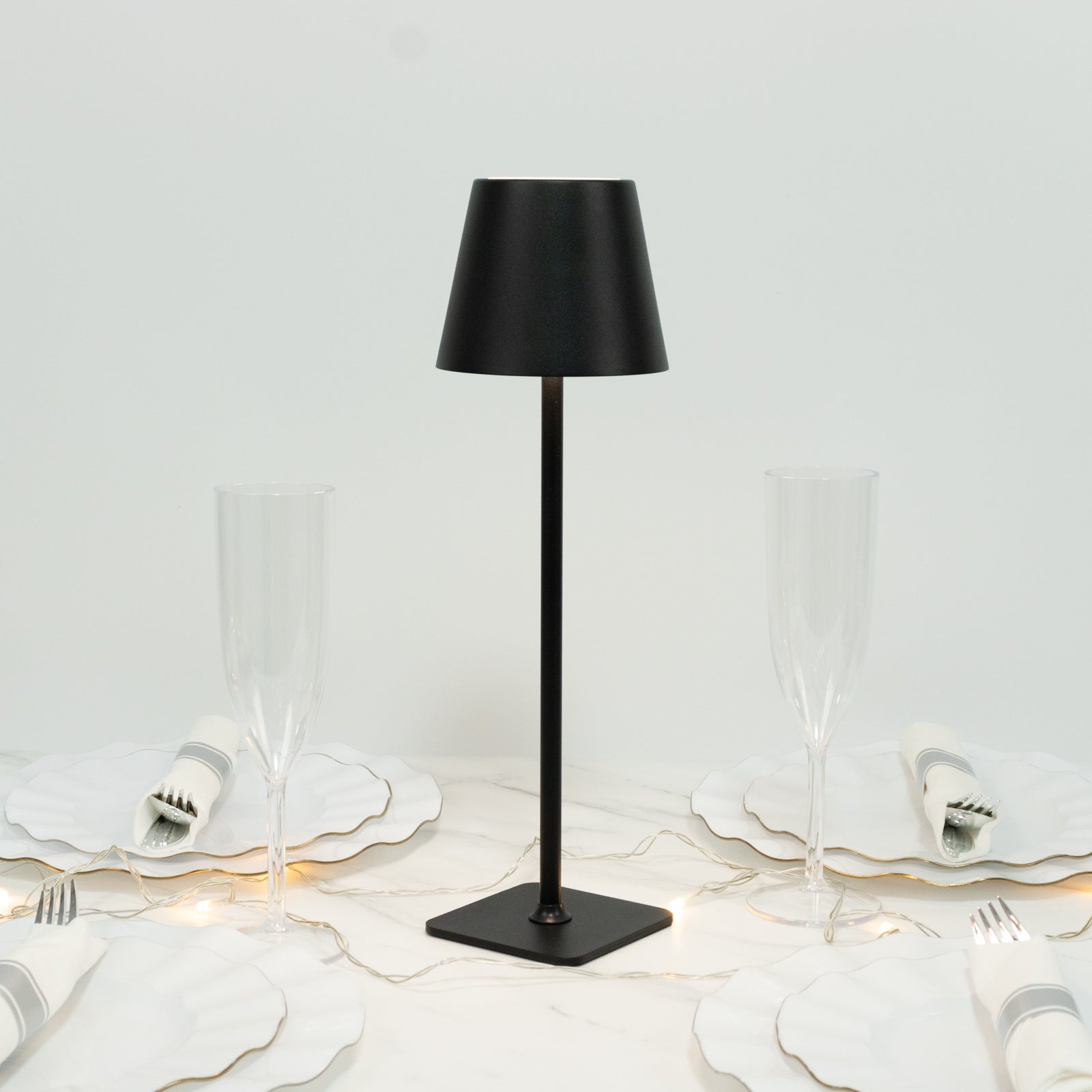 Black metal LED table lamp with classic empire lampshade on a dining table.