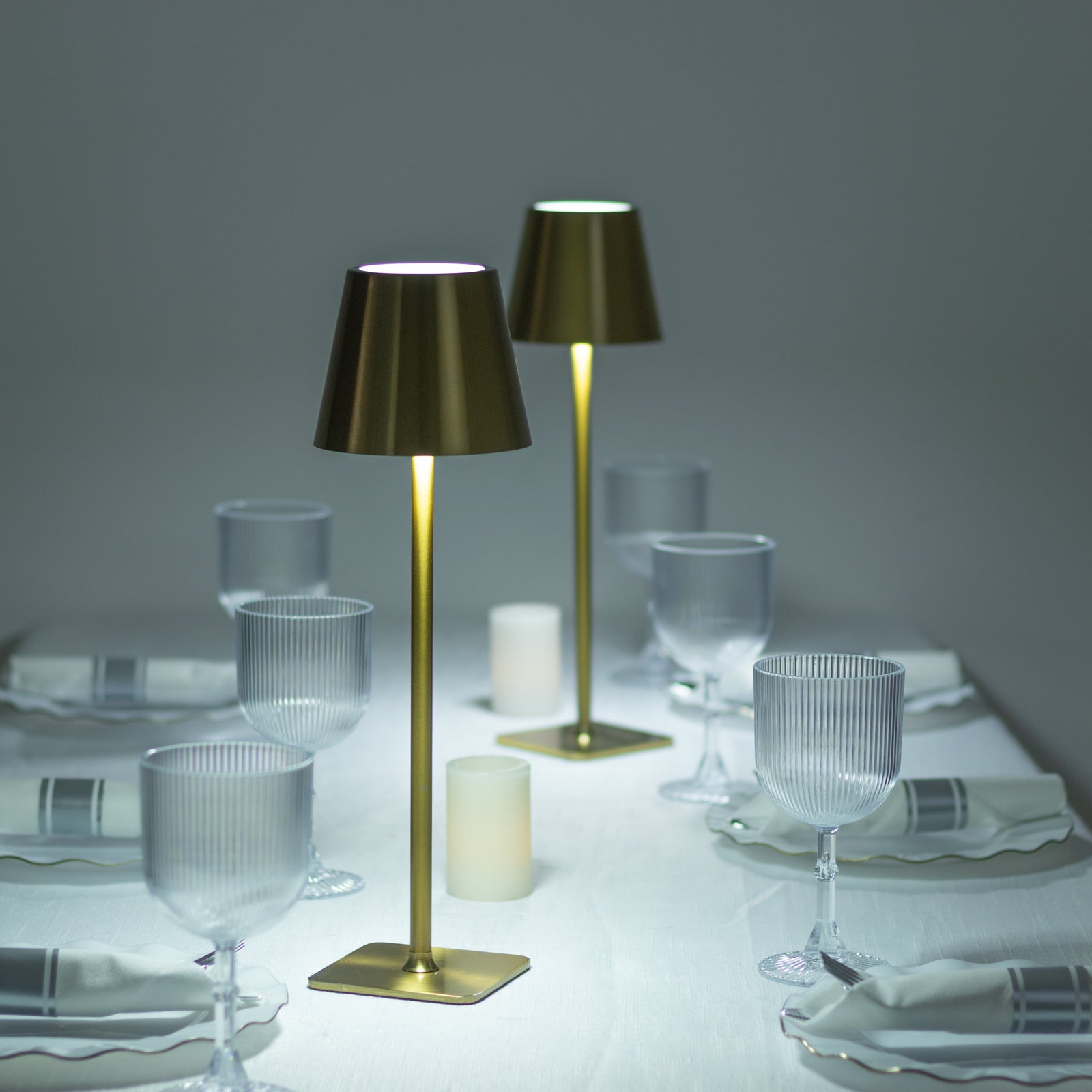 Gold metal LED table lamp with classic empire lampshade on a dining table setting.