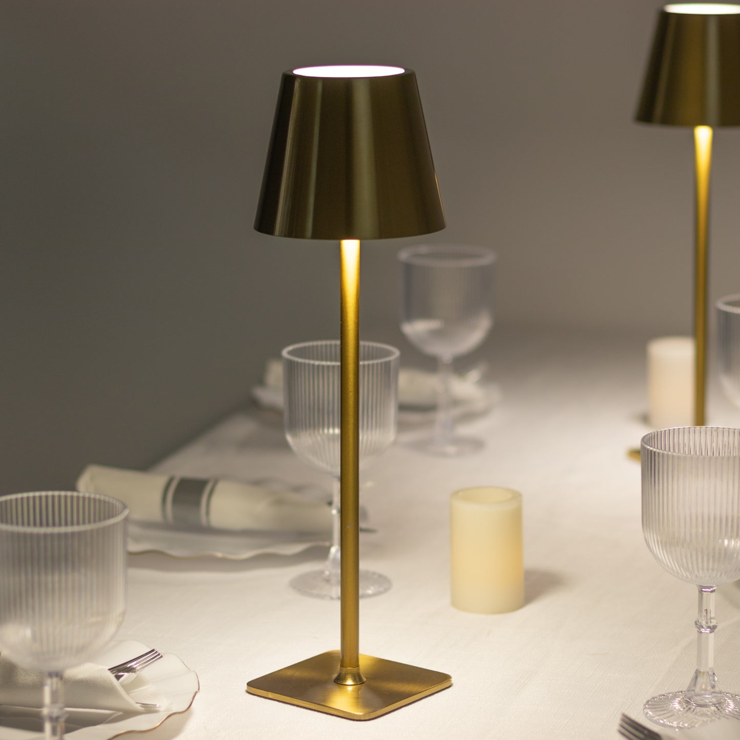 Gold metal LED table lamp with classic empire lampshade on a dining table.