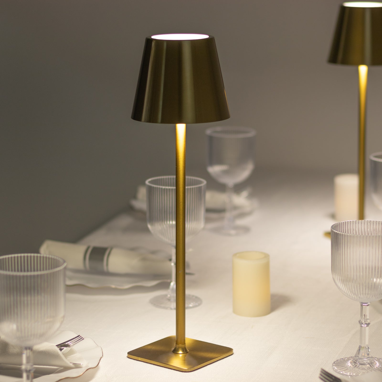 Gold metal LED table lamp with classic empire lampshade on a dining table.