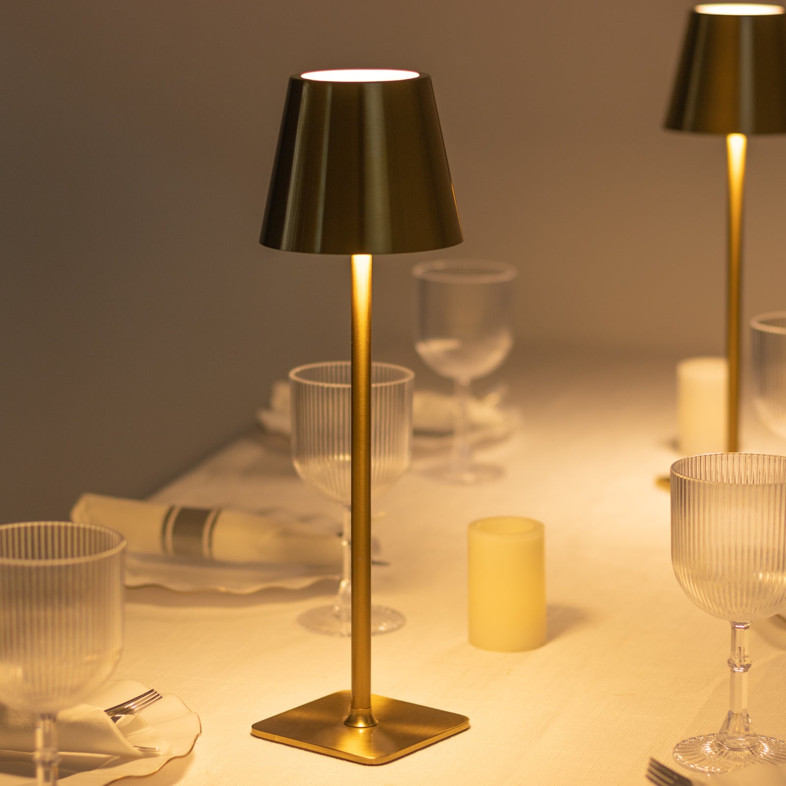 Gold metal LED table lamp with classic empire lampshade on a dining table.