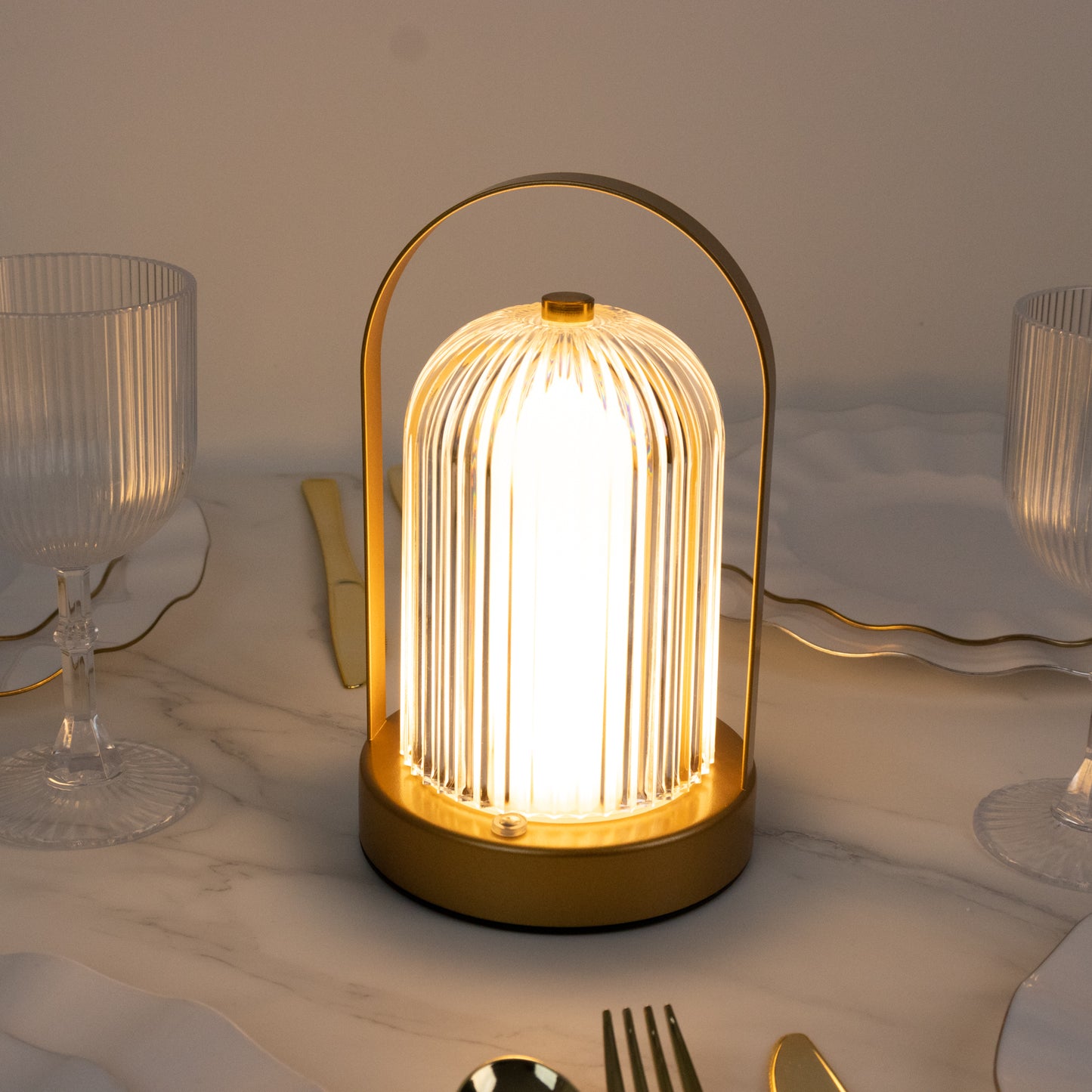 Gold LED table lamp with ribbed acrylic shade on a marble table.
