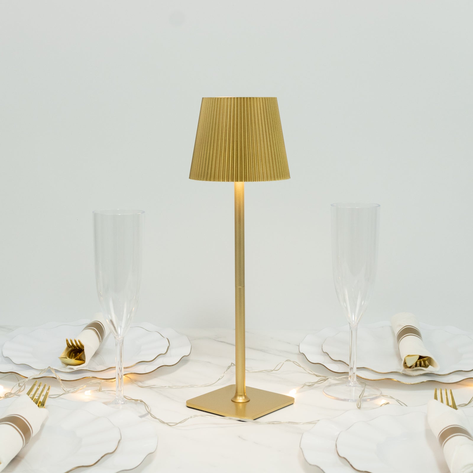 Gold cordless LED table lamp with ribbed shade on a dining table.