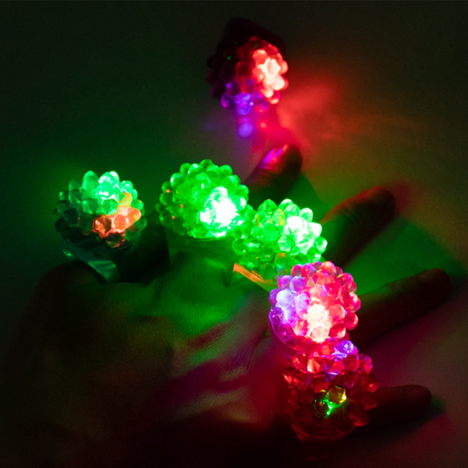 Colorful LED light-up rings in green and red on a hand.