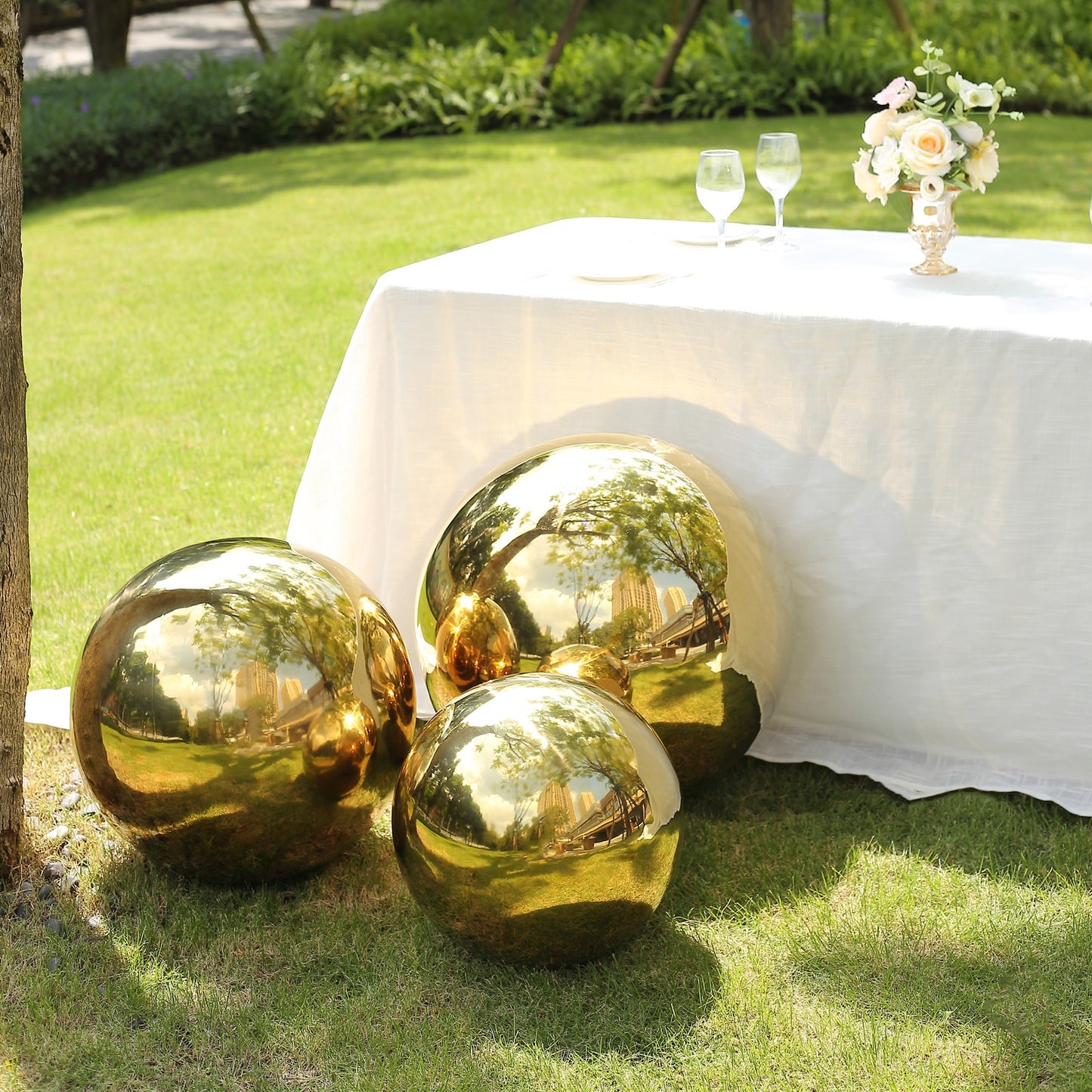 Gold reflective garden gazing ball spheres on green grass.