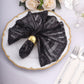 Black geometric sequin cloth napkin on a decorative plate.