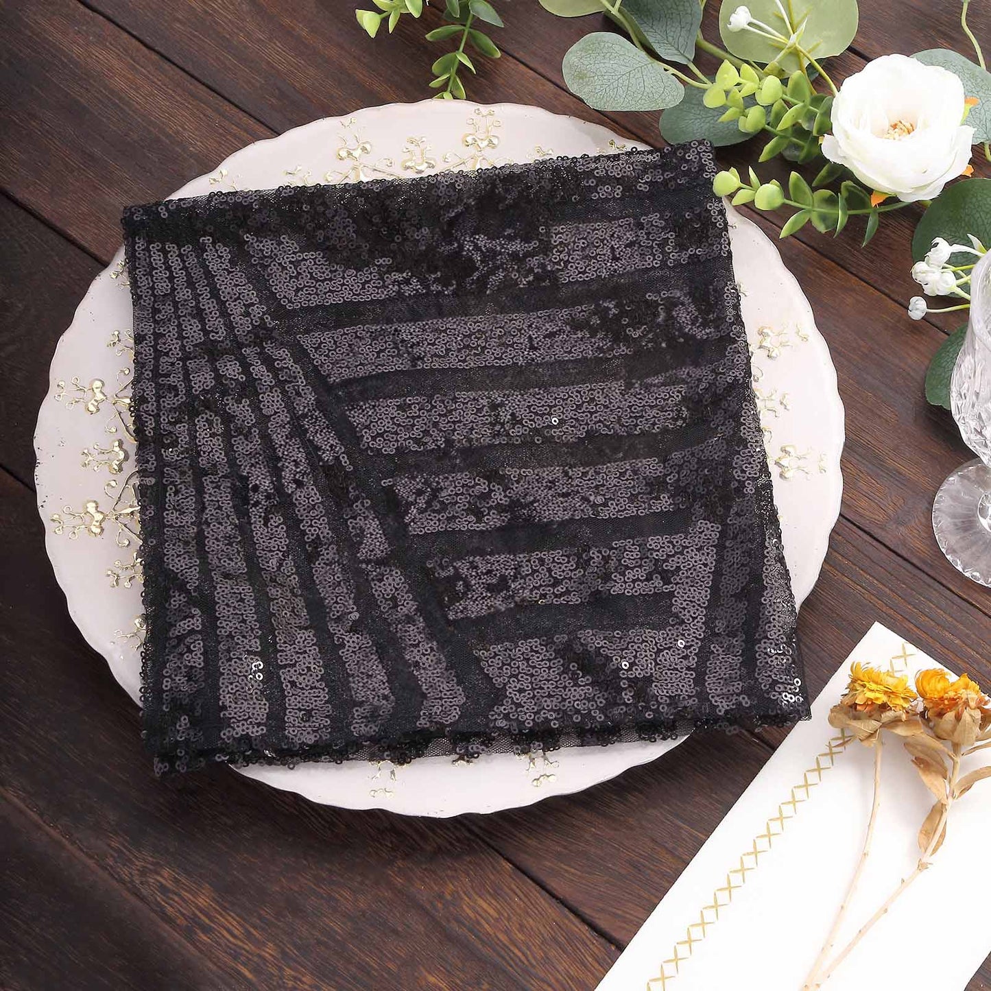 Black geometric diamond sequin napkin on decorative plate.