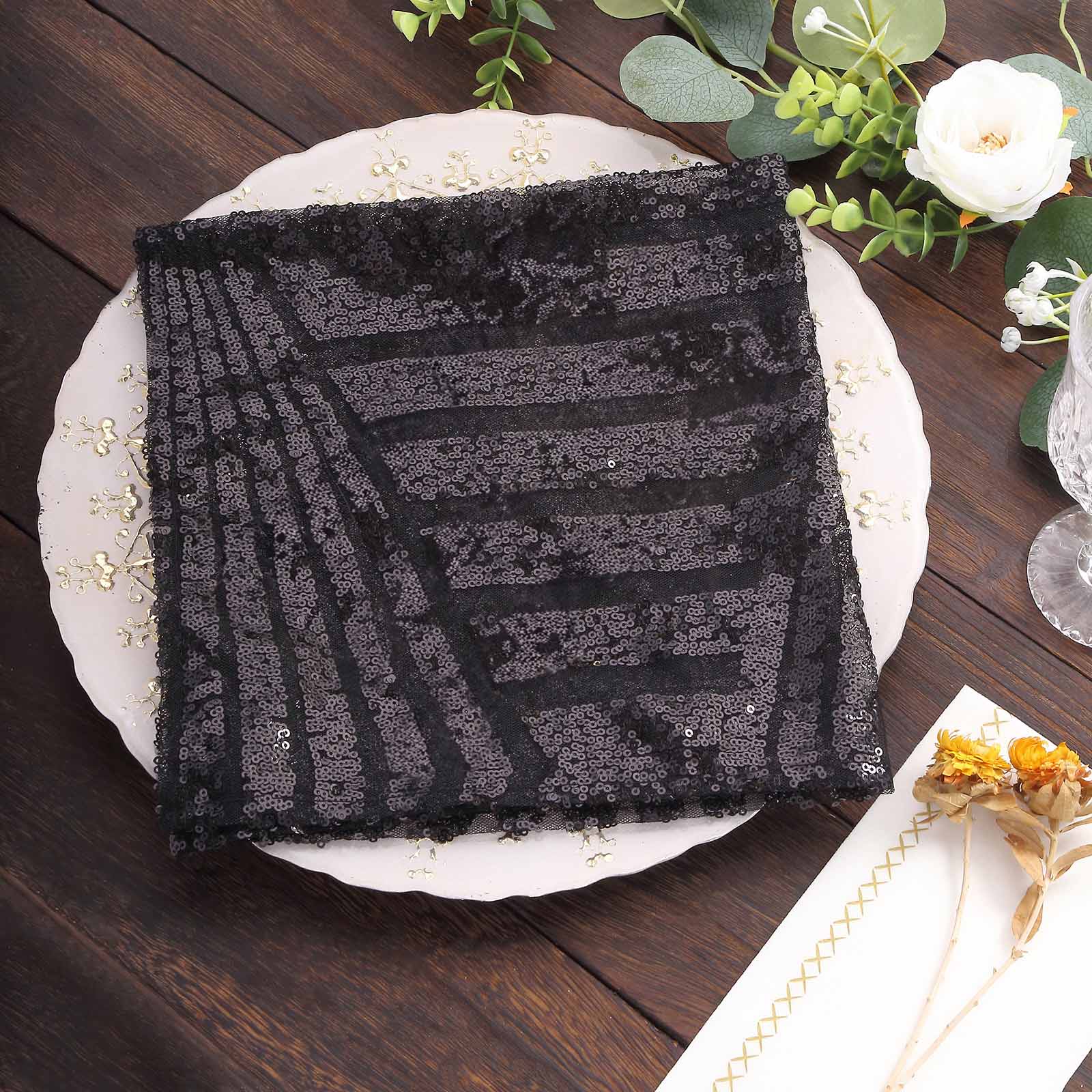 Black geometric diamond sequin napkin on decorative plate.