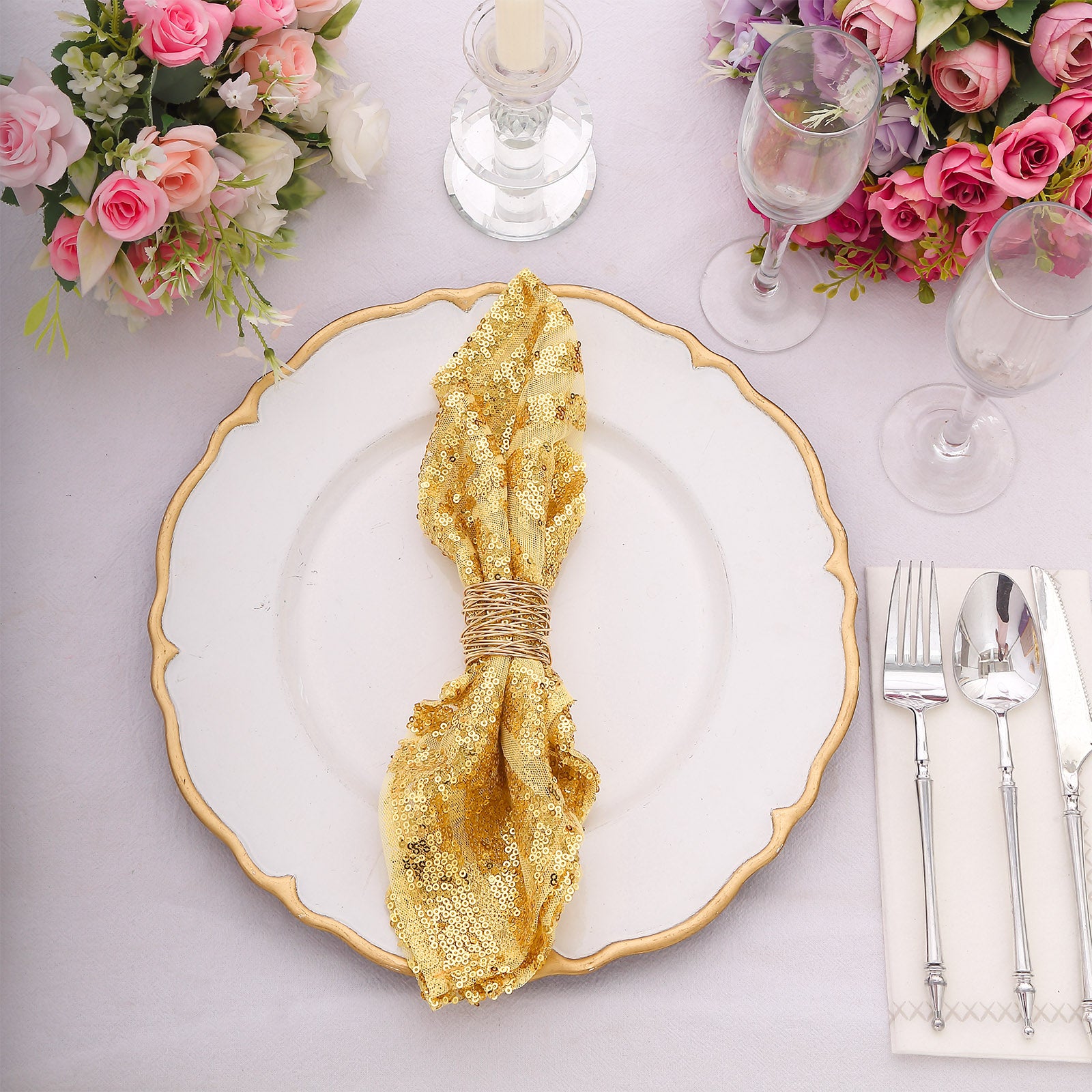 Gold sequin cloth napkin on a decorative plate with floral arrangements.