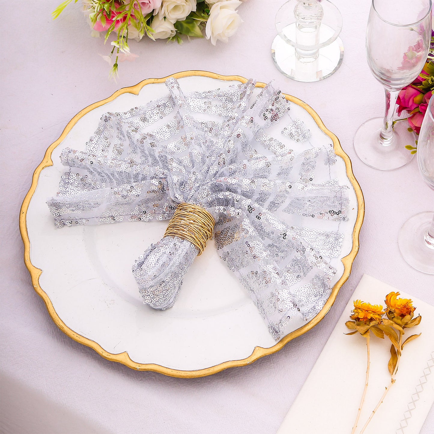 Silver geometric diamond sequin cloth napkins on a decorative plate.