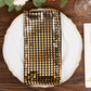 Shiny black and gold foil dinner napkin on a white plate.