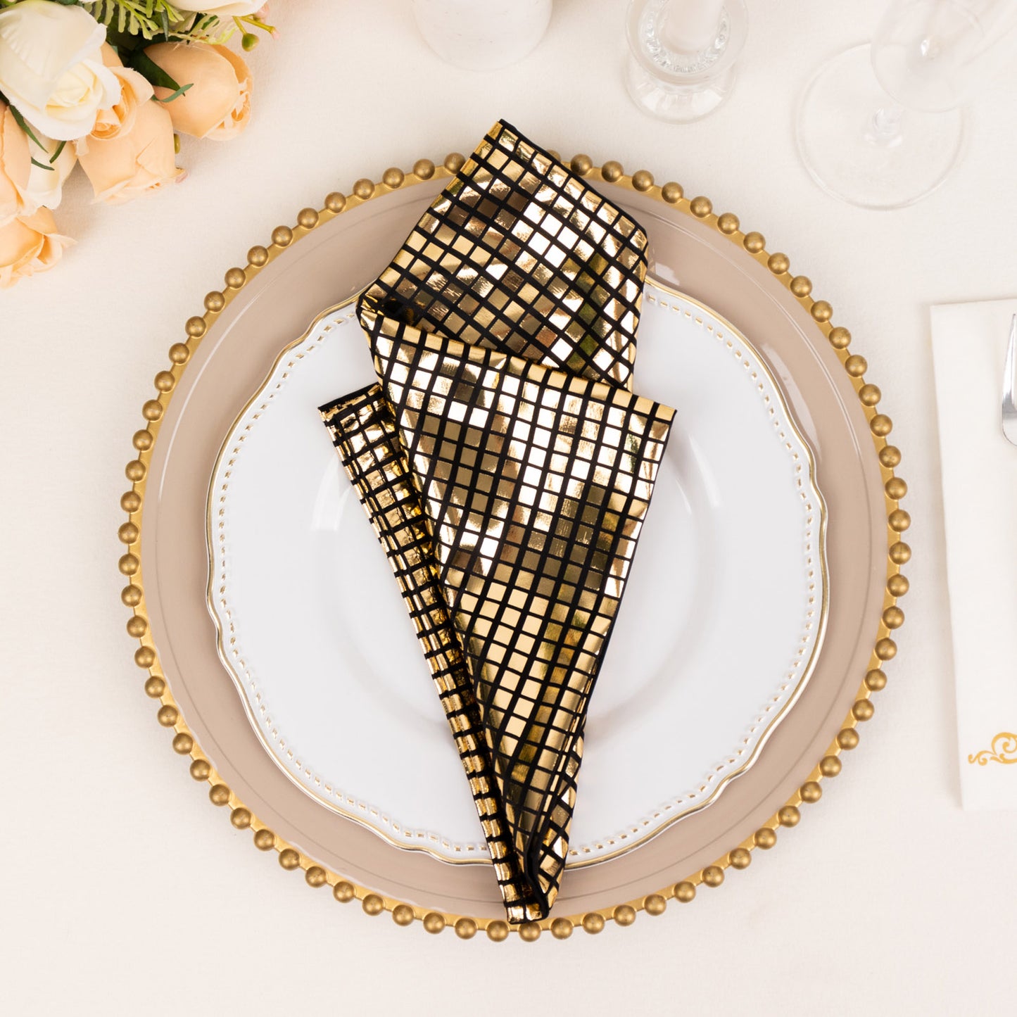 Shiny black gold foil cloth dinner napkins on a decorative plate.