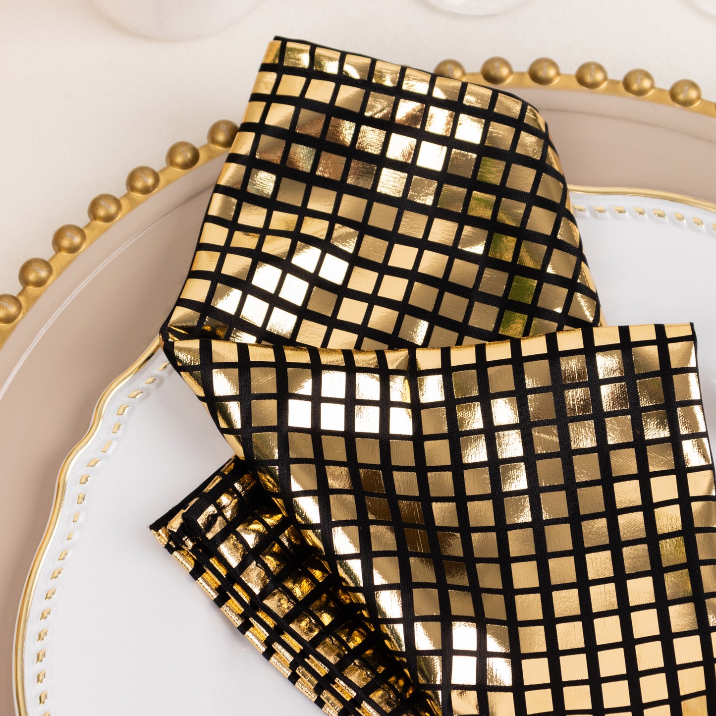 Shiny black and gold foil dinner napkins with a disco mirror ball theme.