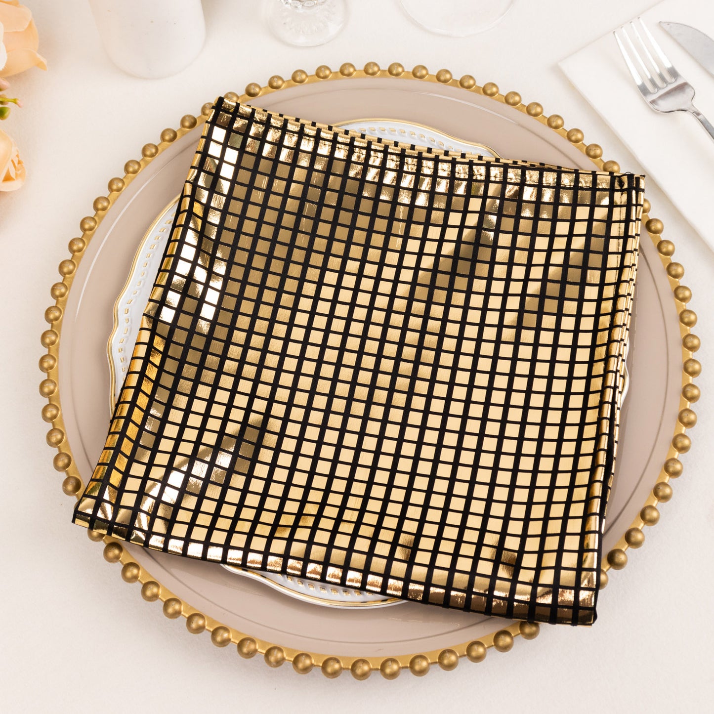 Shiny black and gold foil cloth dinner napkin for a disco theme table setting.