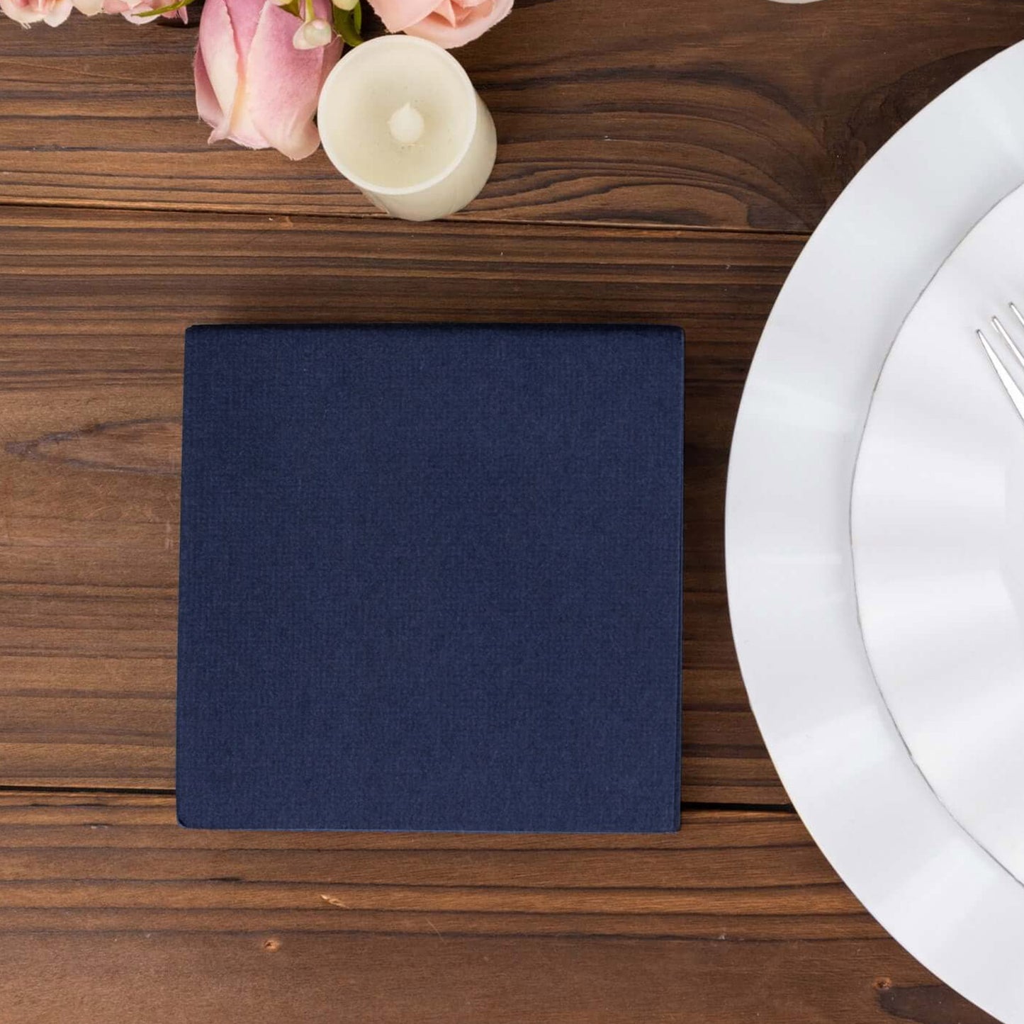 Navy blue linen-feel cocktail napkin on a wooden table setting.