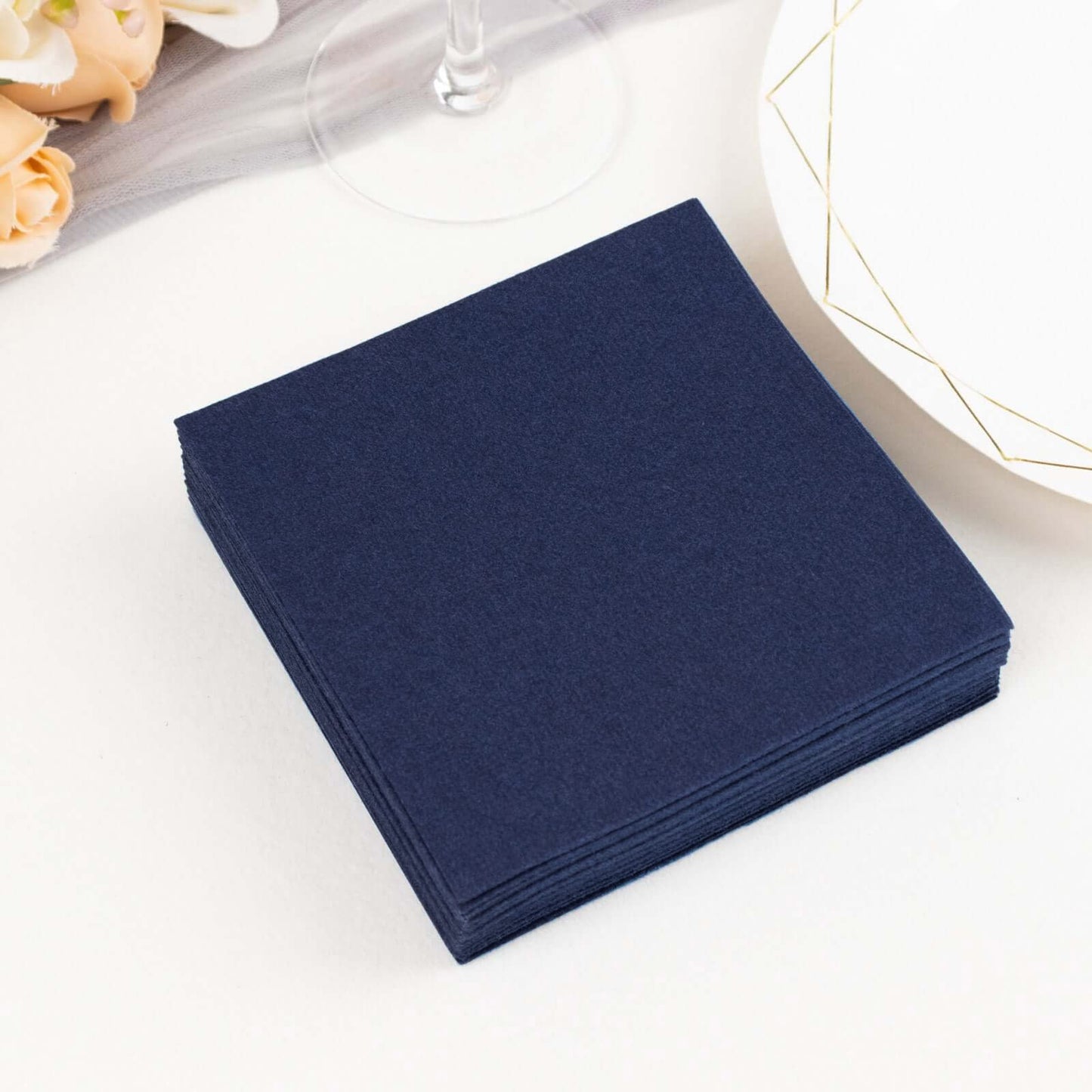 Navy blue linen-feel cocktail napkins stacked on a table.
